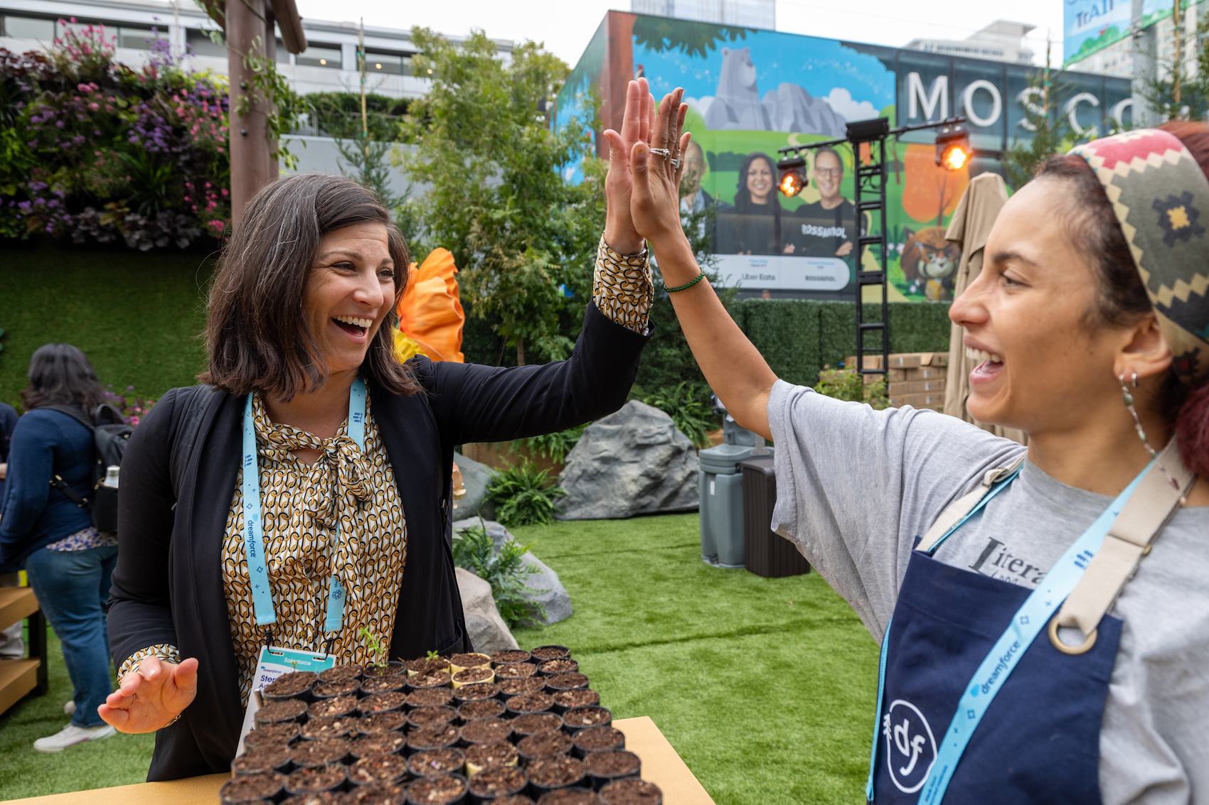 Two women at Dreamforce event by Salesforce high-five after planting seeds