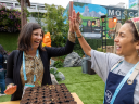 Two women at Dreamforce event by Salesforce high-five after planting seeds