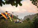 Helicopter landed on a scenic hilltop at sunset, with a couple enjoying a picnic against a mountain background