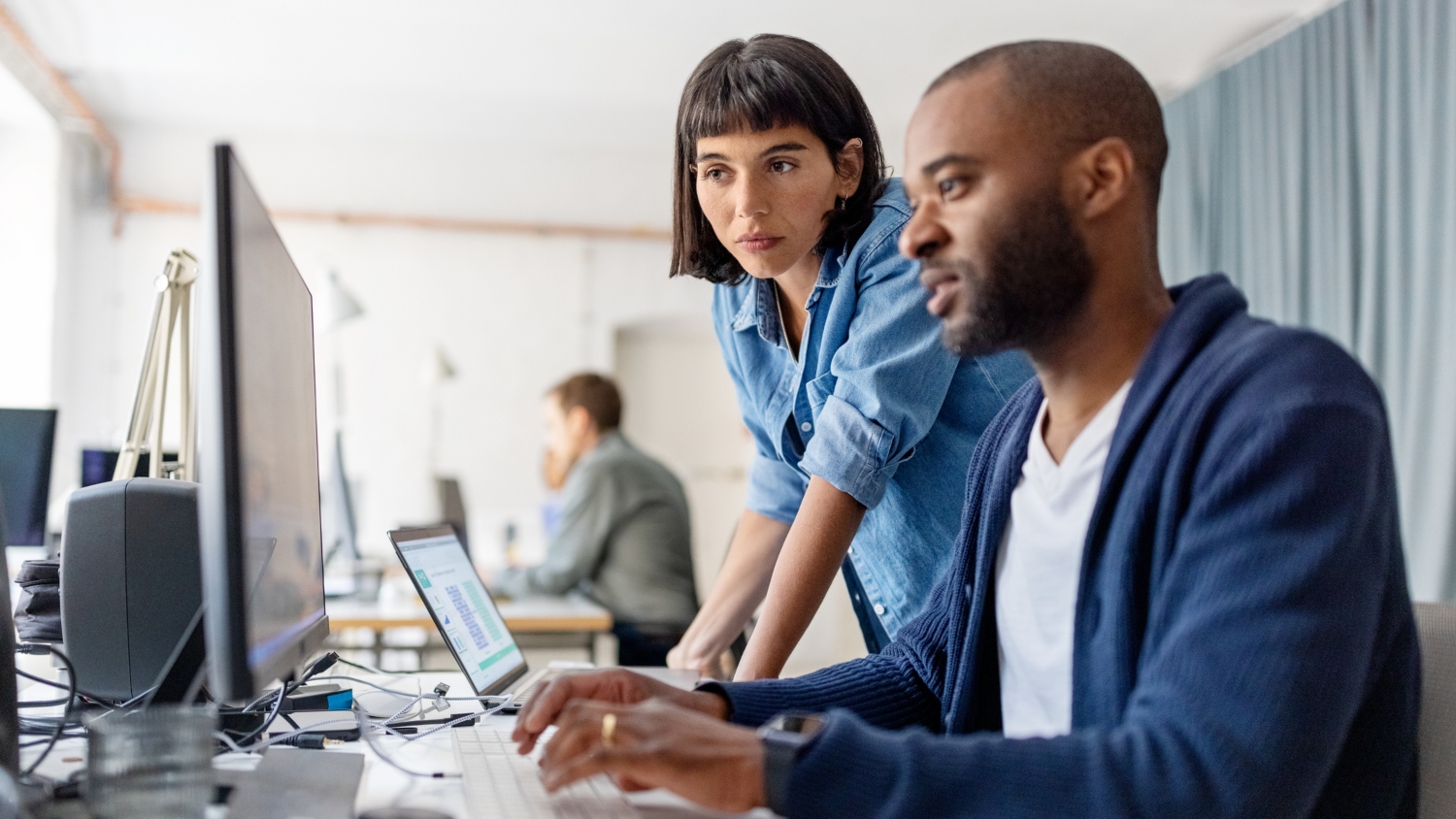 Two people working in front of a computer.