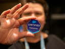 Close-up of a 'Salesforce Certified Professional' badge sticker held in a hand, representing the new AI certification in the portfolio