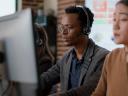 A male customer service representative using headset helps callers.