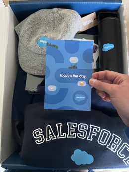 Jose receiving a Salesforce kit, with a card, a cap, a hoodie and a bottle.