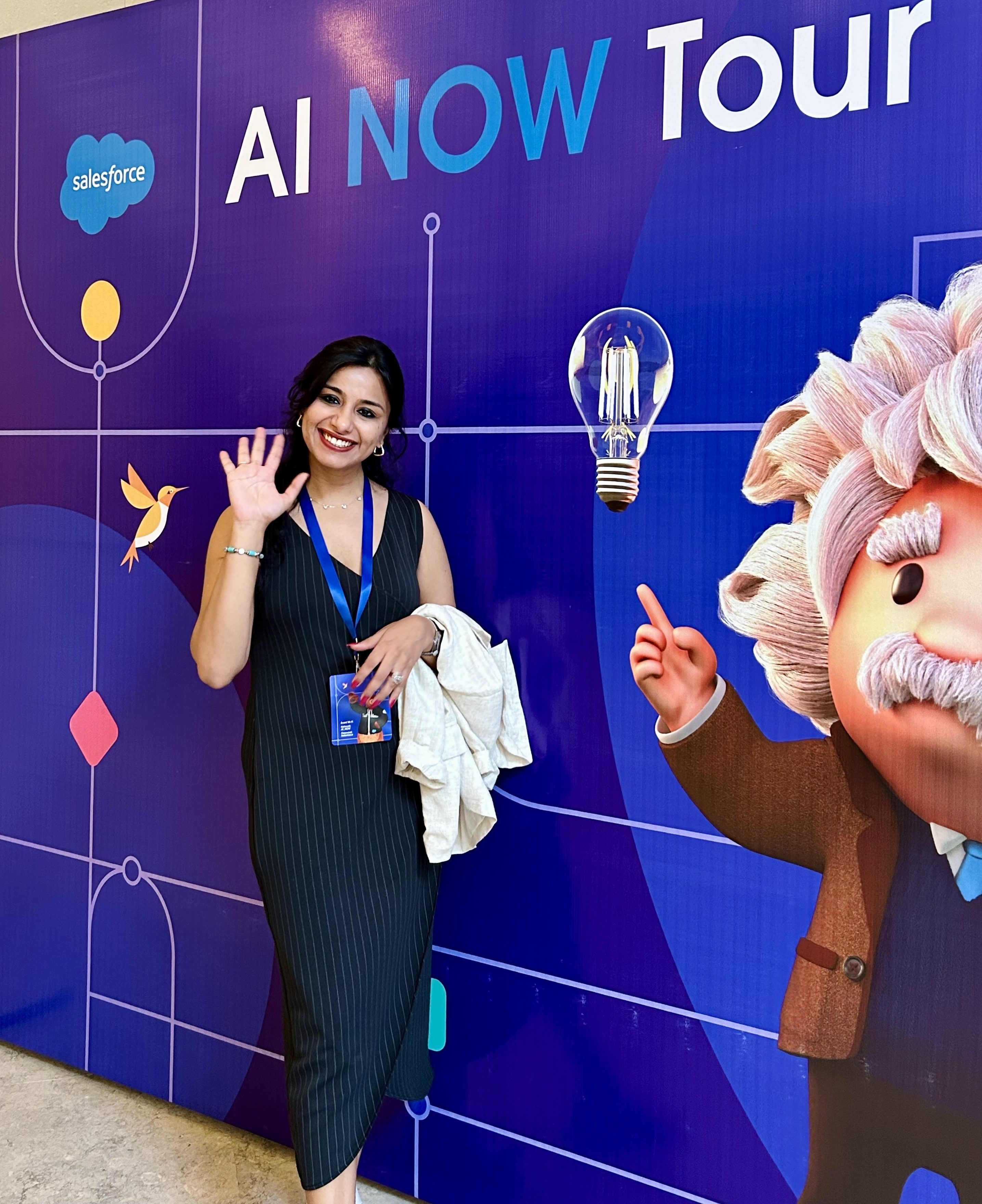 Garima poses next to an AI NOW Tour poster featuring Einstein and a purple background