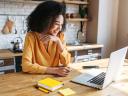 A woman at her counter smiling at a laptop, showcasing a side hustle job in her spare time.