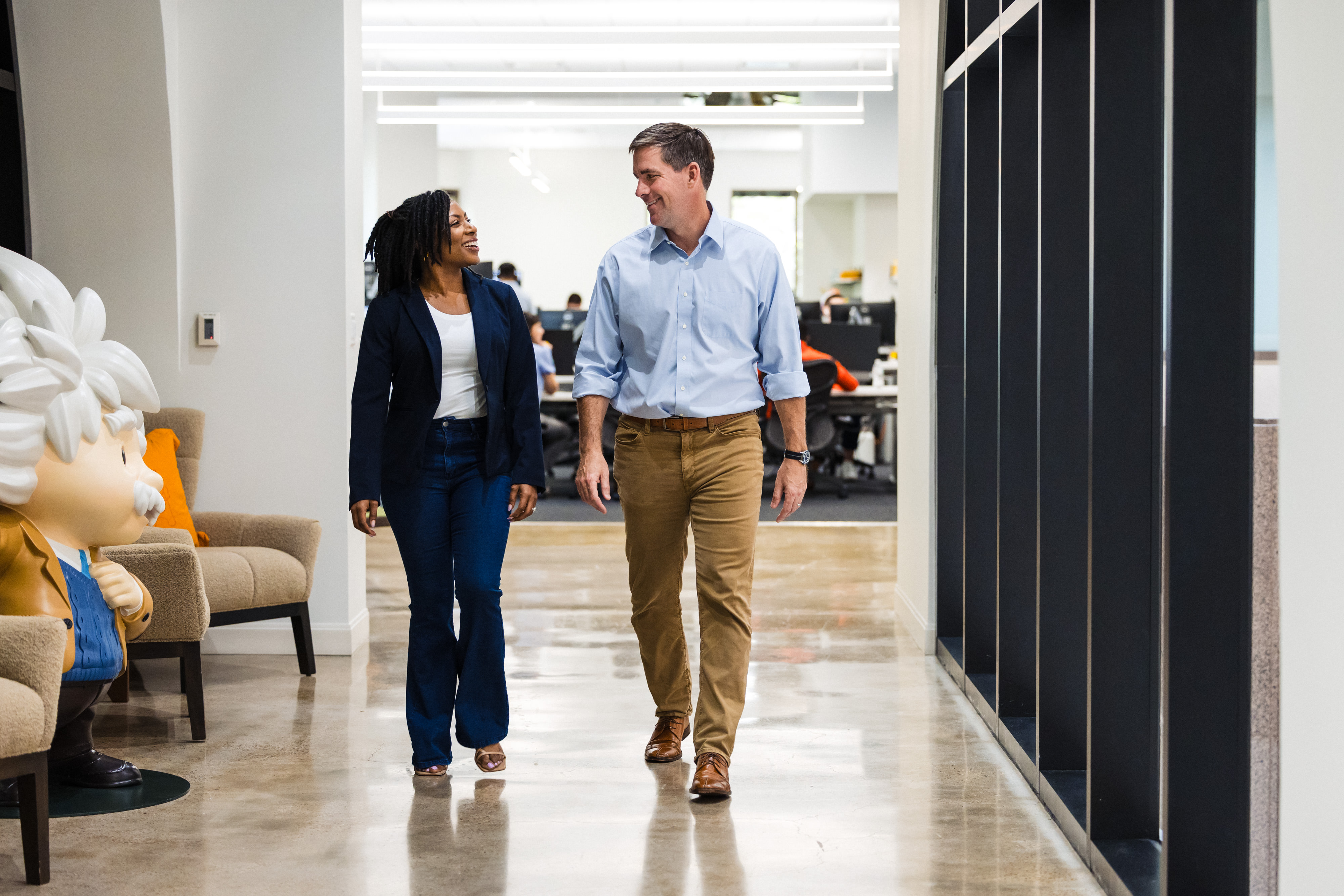 A woman and a man walk down a hallway
