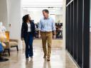 A woman and a man walk down a hallway