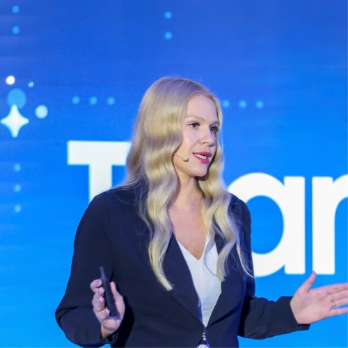 Veronica speaking onstage in front of a blue screen