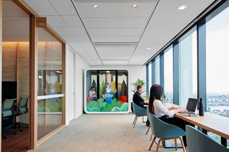 A corner of the Salesforce office with a conference room, laptop bar, and privacy booth decorated with Salesforce characters