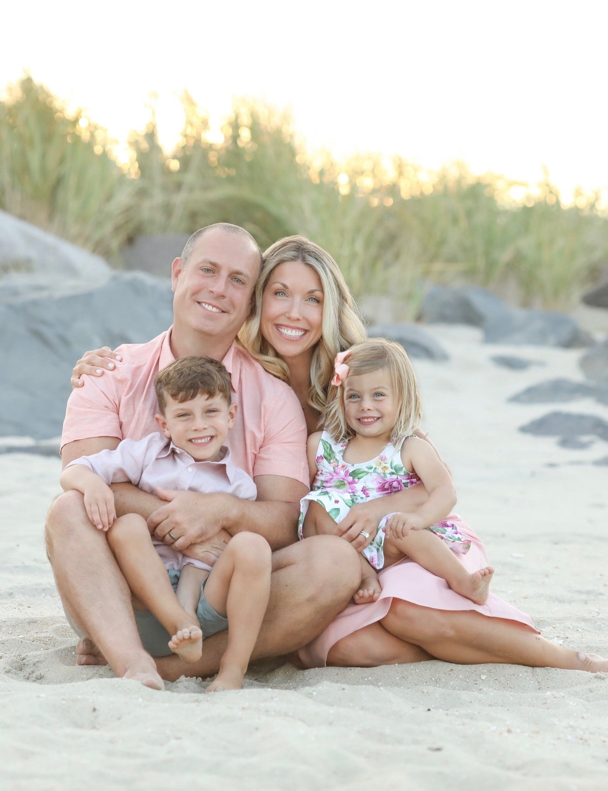 Sarah, her husband, and two young children on a beach at sunset