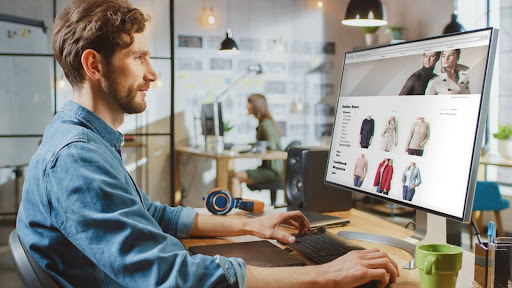 A man in a shop writing blogs on a computer to help his online storefront.