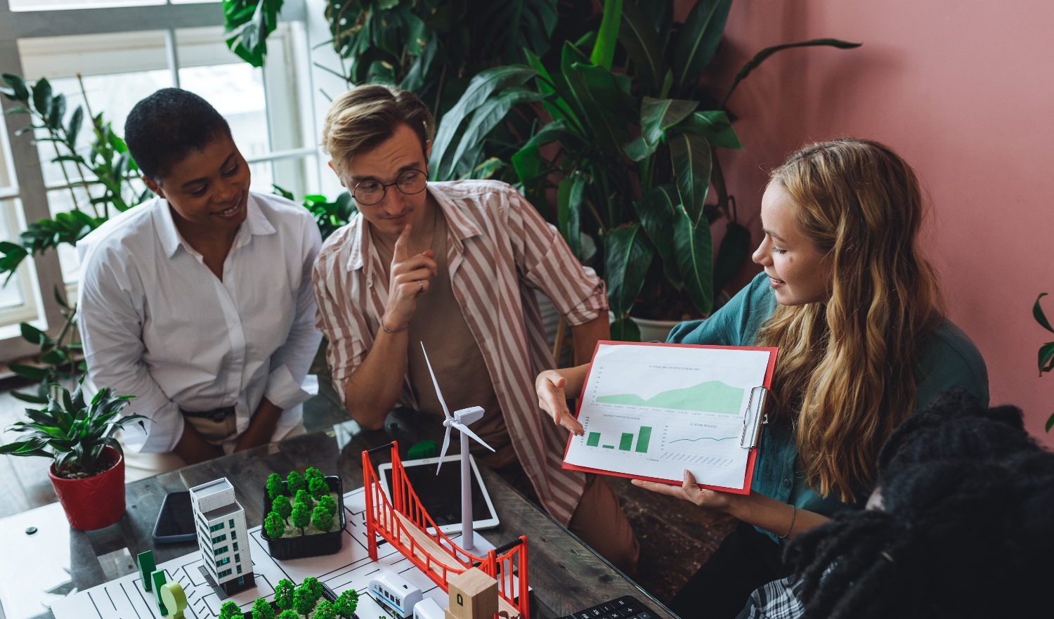Three people looking at a pitch deck in an office around a model.