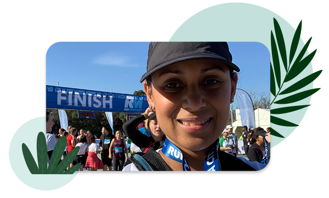 Valéria wearing a finishing medal in front of a marathon finish line