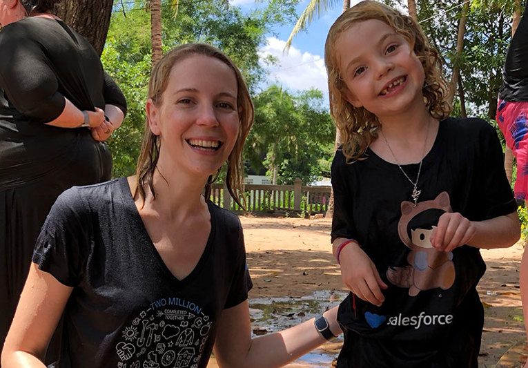 Amanda with her daughter in Salesforce shirts pose together after the water blessing ceremony in Cambodia.