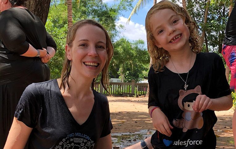 Amanda with her daughter in Salesforce shirts pose together after the water blessing ceremony in Cambodia.