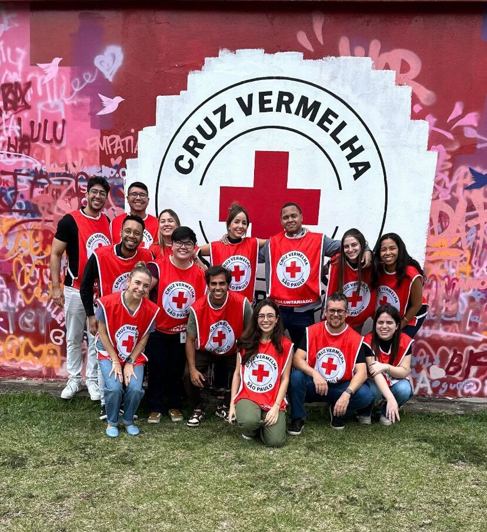people wearing vests that have a red cross standing in front of a sign that says "Cruz Vermelha"