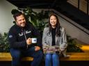 Two Salesforce employees sit next to each other, smiling. One holds a coffee mug and the other holds a laptop.