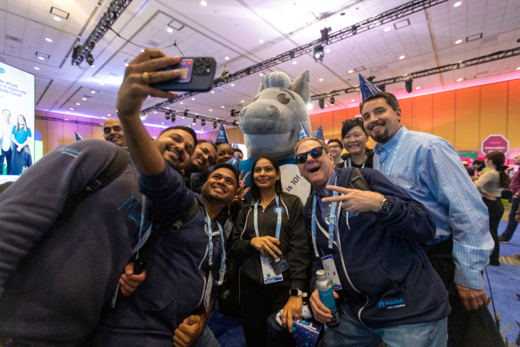 A group of smiling people huddle together for a selfie at Dreamforce.