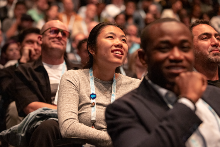 People smiling in the audience of a presentation at Dreamforce.