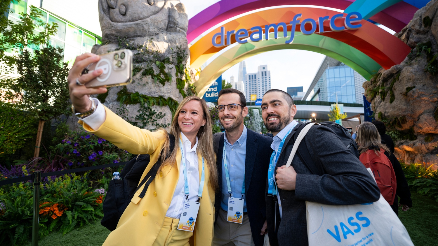 Three attendees smile while taking a selfie together outdoors at Dreamforce.