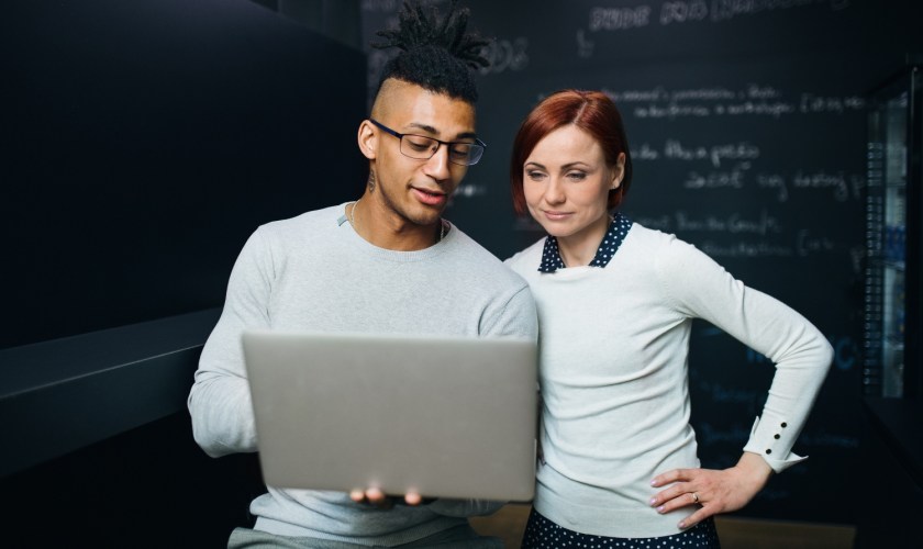 A team of two review Data Cloud and Salesforce Foundations on a computer in front of a black data screen.