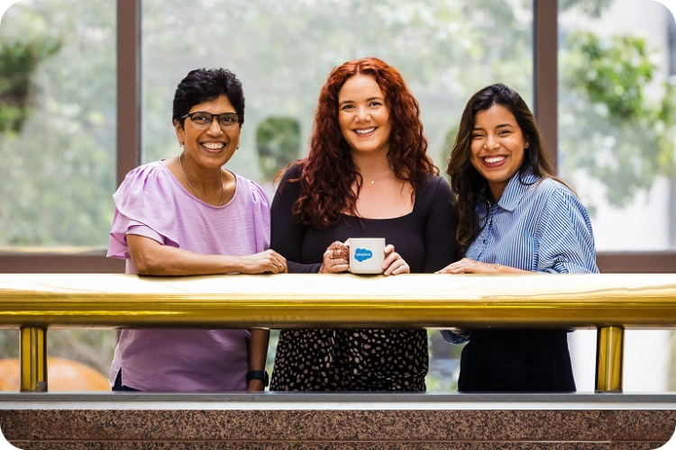 Three women, Salesforce employees smiling and are sharing some time together.
