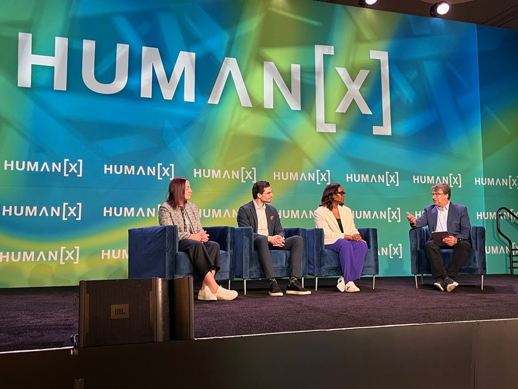Panel of four speakers seated on stage during the HUMAN[X] event.
