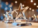 A table with three, star glass awards and blurry lights.