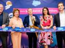 A group of five people is celebrating the opening of the Salesforce Amsterdam office with a ribbon-cutting ceremony.