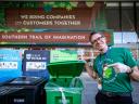 A Salesforce volunteer poses in front of compost, recycling, and trash bins at Dreamforce.