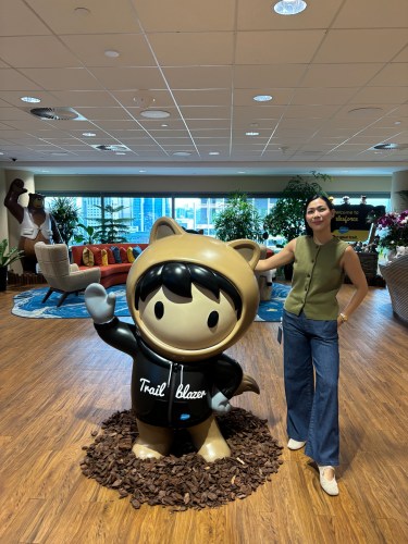 woman stands in a modern office space next to a life-sized astro statue