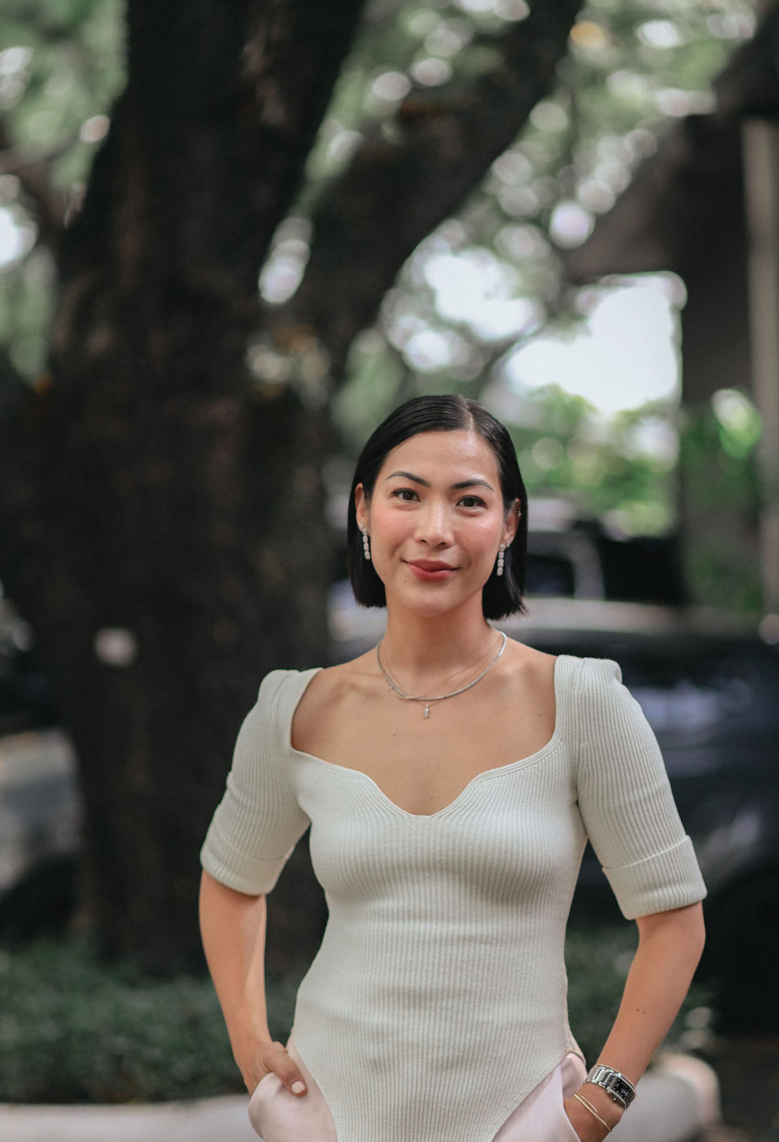 woman stands outside for a professional photo in a cream top