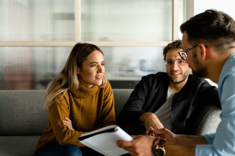A business owner woman listening to small business advice from a man and another man on a couch.