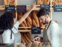 Two local bakery owners reviewing a data driven marketing strategy pointing at their bread at the counter, calculating.