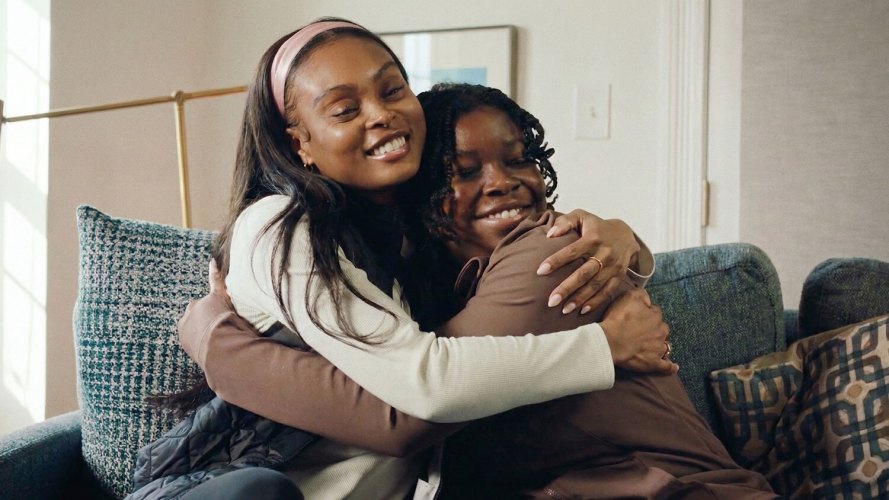 Two women sharing a joyful hug on a couch.
