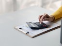 Businesswoman using a calculator to calculate numbers on a company's financial documents, calculating CPL.