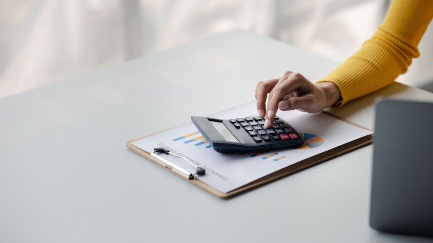 Businesswoman using a calculator to calculate numbers on a company's financial documents, calculating CPL.