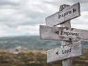 inspire empower lead text engraved on wooden signpost outdoors in nature. Panorama format.