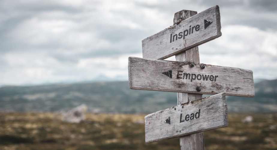 inspire empower lead text engraved on wooden signpost outdoors in nature. Panorama format.