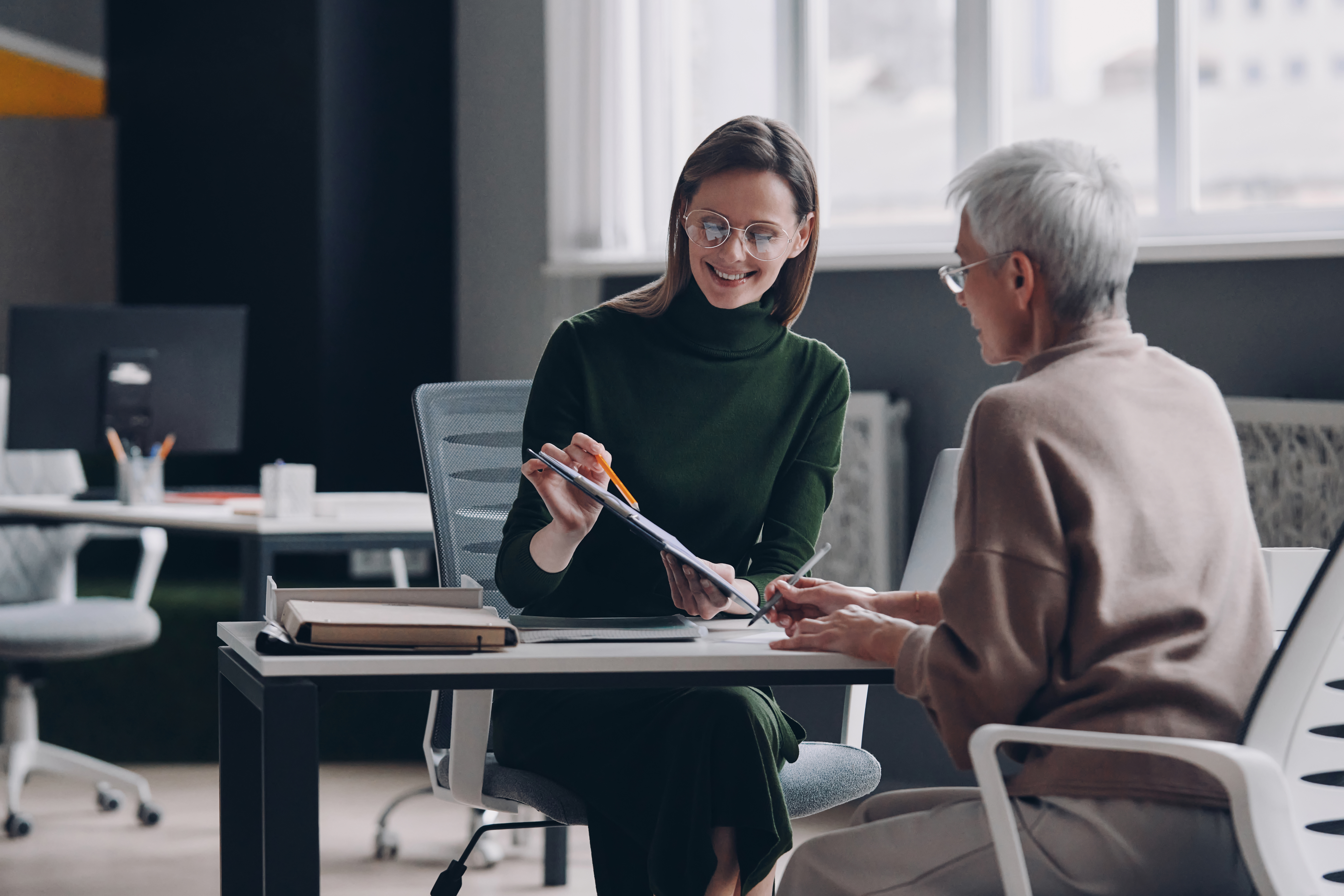 Senior woman discussing options with financial advisor while sitting in the office together