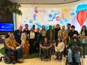 Members from the Center for Independent Living with Workforce Navigators Analyst, Lucia Rios, during a visit to Salesforce Tower in San Francisco. Behind them, a digital screen with Salesforce characters and the cloud logo.