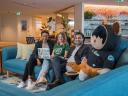 four employees sit on a couch in a modern office space