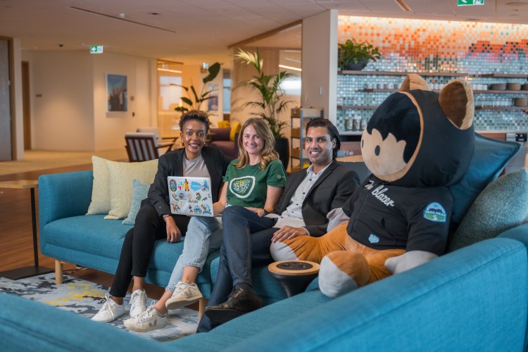 four employees sit on a couch in a modern office space