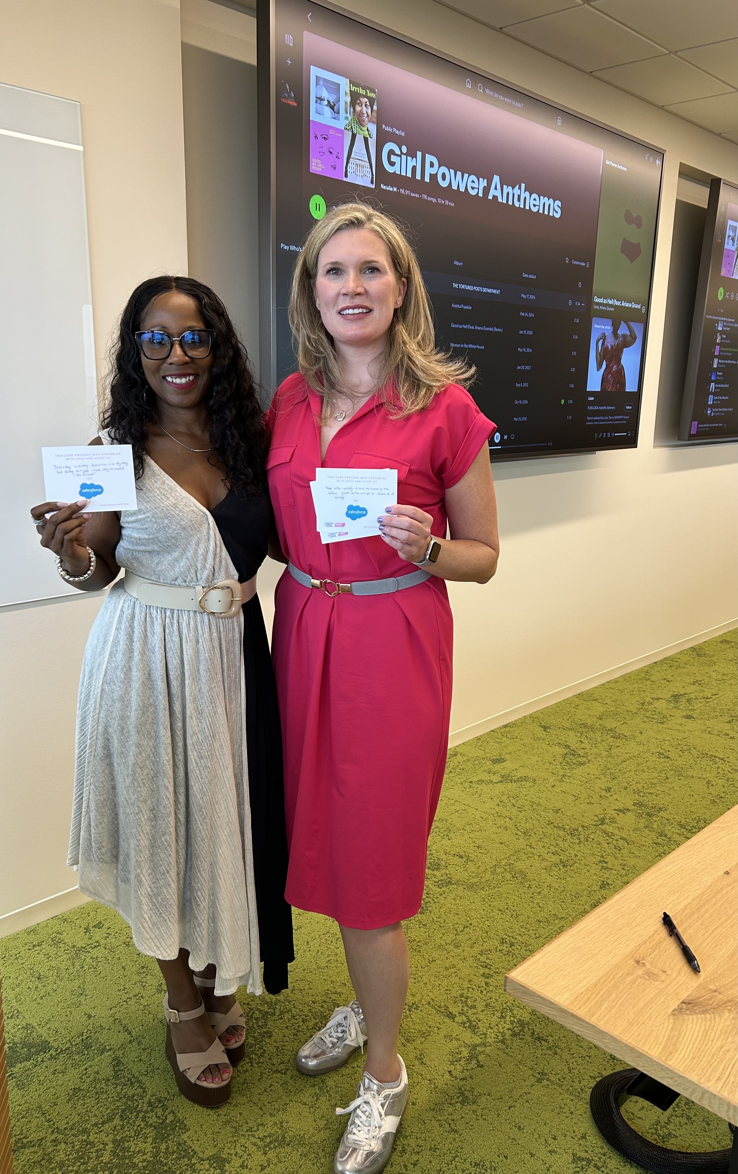 Two women pose together in a modern office space