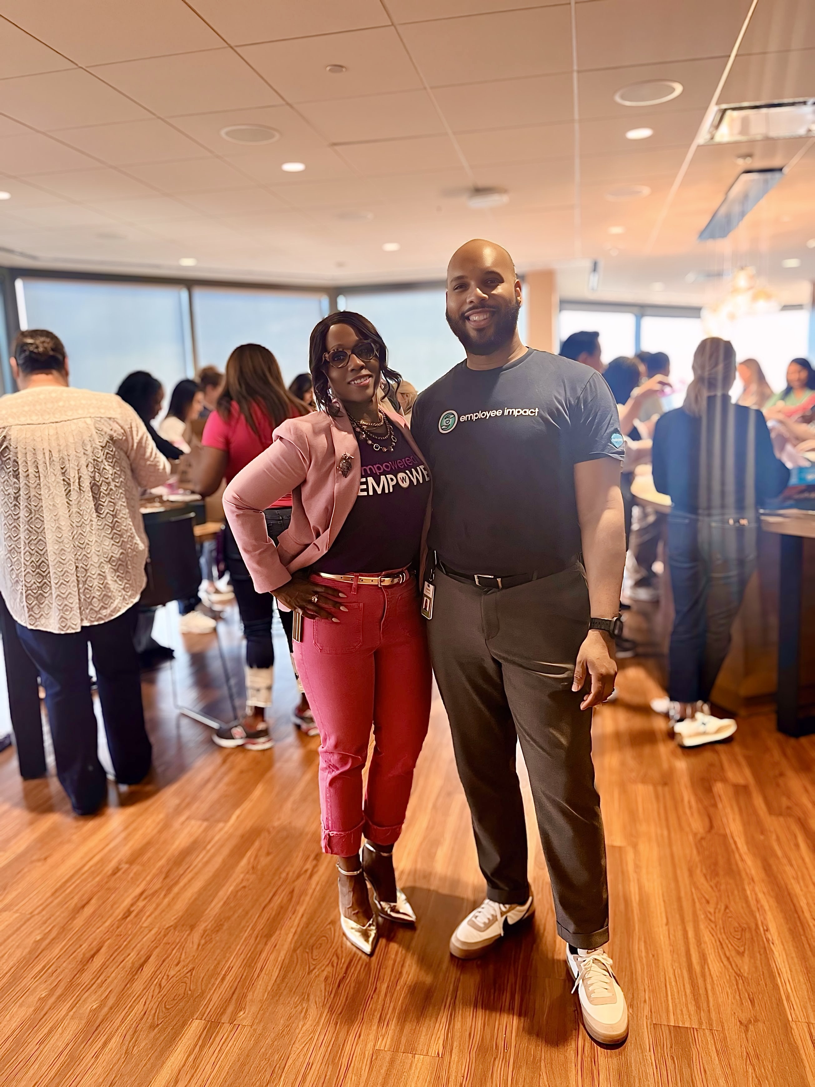A man and woman pose for a photo inside a modern office space.