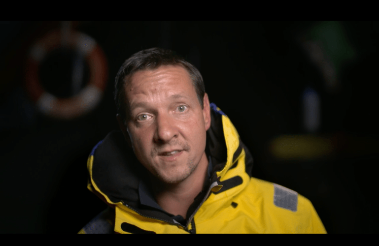 Andy Butterfield, Agentic AI GTM Lead at Salesforce, in a yellow reflective jacket speaking to the camera. It is nighttime.