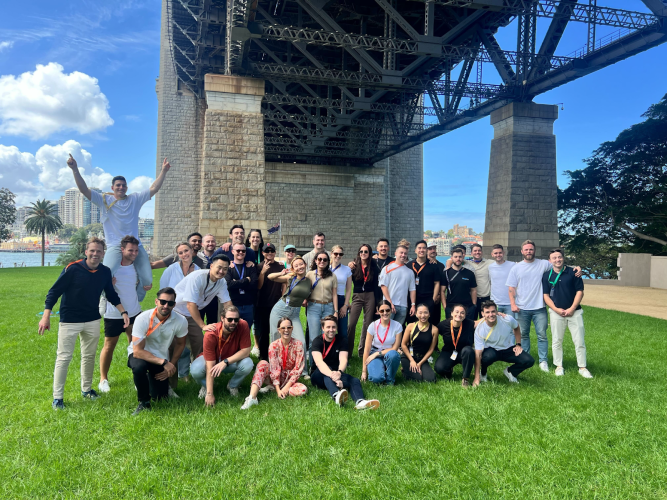 group of employees pose under a bridge outside