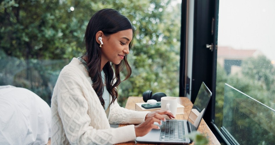 Earphones, laptop and remote work with woman at window in home for online planning or leading a team asynchronously.