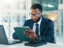 Investor, tablet and black man in workplace, reading and website blog for economy news.