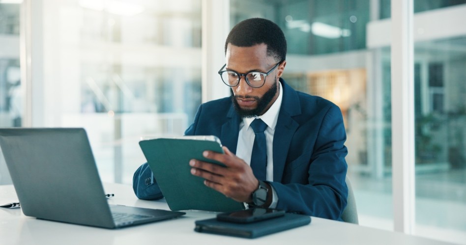 Investor, tablet and black man in workplace, reading and website blog for economy news.